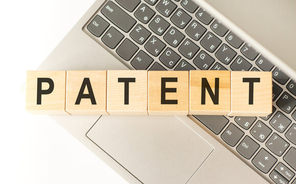 Word patent. Wooden cubes with letters isolated on a laptop keyboard. Business Concept image.