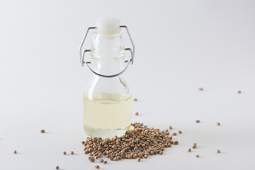A little bottle of hemp oil and seeds on white background