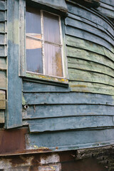 window of an old boat house with rotten wood and different green paint