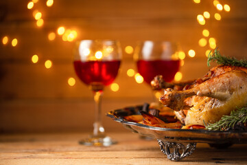 Festive dinner served on wooden table with lights background. Holiday concept.