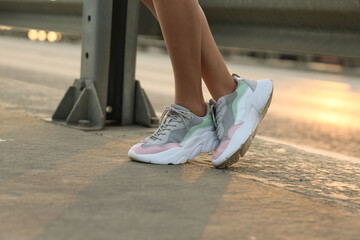 female legs in sports sneakers close-up on the street outdoors