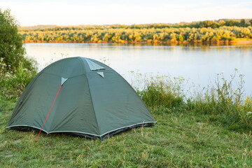 tourist tent is by the river in summer at sunset.