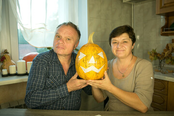 The pumpkin is ready for slicing. The man and the woman are happy with their work and laugh and...