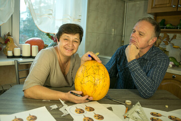 The pumpkin is ready for slicing. The man and the woman are happy with their work and laugh and...