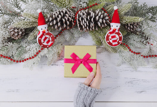 Hand and gift.
Female hand and gift with pink ribbon on white wooden table with christmas decr, top view.