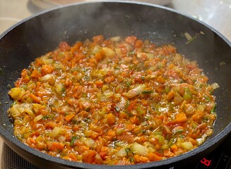 chopped vegetables in sauce are fried in a Frying pan