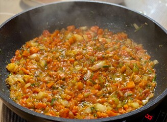 chopped vegetables in sauce are fried in a Frying pan