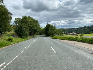 Looking down, Huddersfield road, with fields, trees, and buildings, on a cloudy day near, New Delph, Oldham, UK