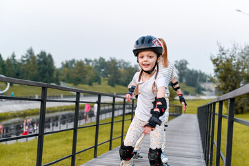 Young mother and her daughter rollerskating in summer day