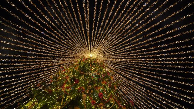 Beautiful illumination in the form of a tent over the New Year tree in the city.