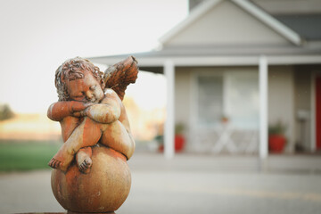 Close up image of stone cherub statue in front garden of newly built house