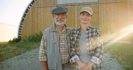 Portrait of gray-haired Caucasian old man with young beautiful woman standing outdoor in hugs and...