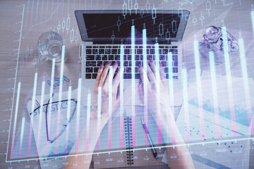 Double exposure of woman hands working on computer and forex graph hologram drawing. Top View. Financial analysis concept.