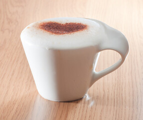 Cup of coffee with cinnamon heart on milk foam
