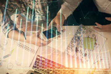 Double exposure of forex graph drawing and man and woman working together holding and using a mobile device. Trade concept.