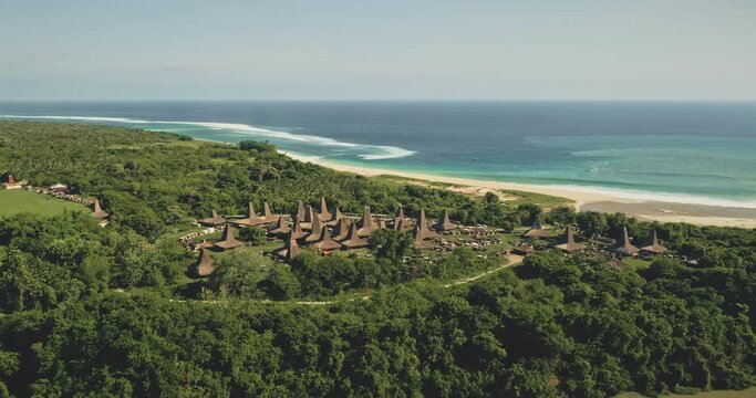 Slow motion of traditional rural houses at Kodi village, Sumba Island, Indonesia. Aerial view of tropic countryside with buildings landmark at sea bay coast. Cinematic drone shot of summer vacation