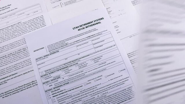 Conceptual composition. Pension savings. Man puts on the table Blank form Investment contract 401(k) or 457 plan, blank form Utah retirement system 401(k) and Personal 401k plan . Close-up
