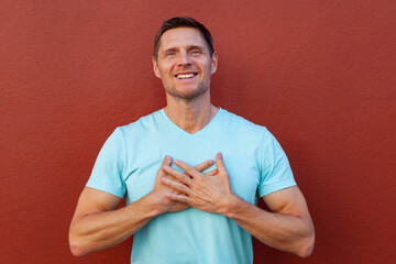 Happy lovely and carefree smiling caucasian man, bowing feel flattered and touched, hold hands on...