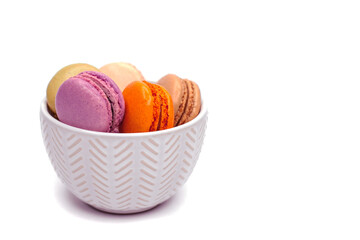 Colored homemade organic macaroons cookies lie in a cute white plate on wight background. Concept of sweet food and desserts on isolated background.