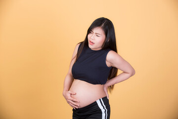 Happy pregnant woman on a yellow background, maternity readiness