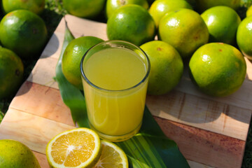 jugo de naranja sobre tabla acompañado de naranjas frescas 