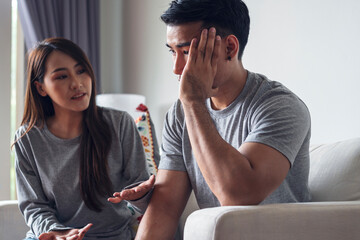 Obraz premium Unhappy young man have problems being quarrel with his wife sitting on sofa together at living room. Husband has attitude annoyed wife complained he very much. Couple problems in relationship concept.