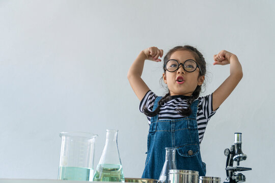 Little 6s cute girl wear glasses happy raise arms with microscope, laboratory bottle and water experiment study scientists while learning success at school. Education science concept.