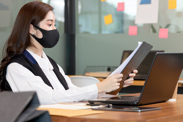 Business woman working job on labtop and wering mask in office.