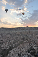 Hot air balloons soar over the mountains and surreal landscape of Cappadocia, Turkey at sunrise