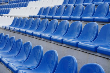 Bleachers in a sports stadium. White and blue seats in a large street stadium.