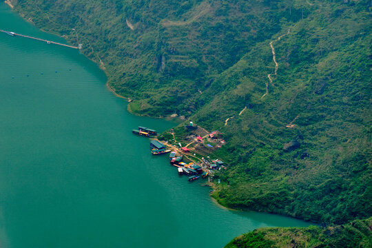 Boats docked in a marina on the bank of the turquoise waters of the Song Nho Que river in Ha Giang, Vietnam