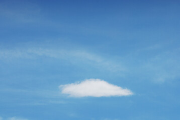 A lone white cloud on blue sky background. Natural single strong bulk cloud. Minimal zen cloud in vast atmospheric space. Clear destiny one vision concept image.