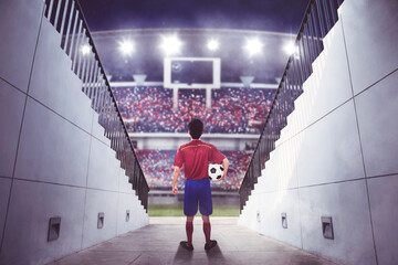 Male soccer player walking into crowded stadium
