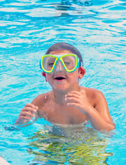 Laughing boy in a swimming pool with swim goggles 