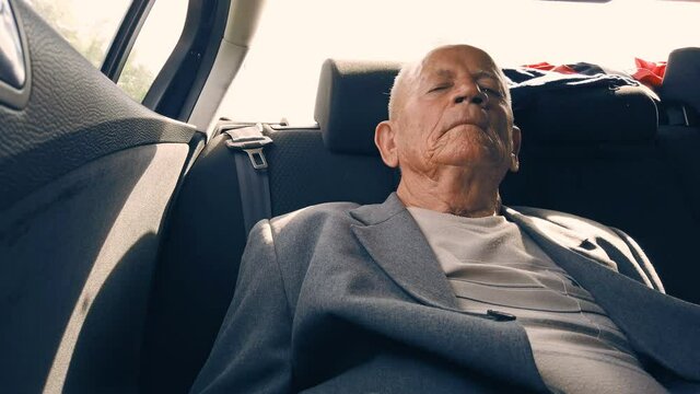 Closeup profile portrait of old mansleeping in car on back seat. Real time