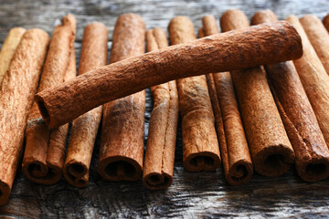 A close up image of several tasty cinnamon sticks on a dark wooden table. 