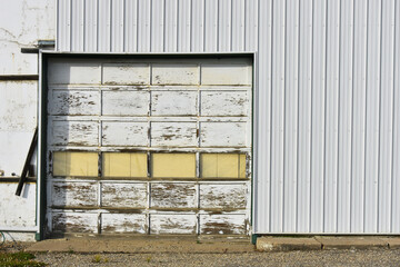 An image of an old weathered and worn industrial overhead door that is no longer used. 