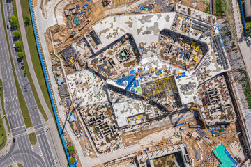 Fototapeta premium aerial topdown view of large building site in city with many construction equipment and materials