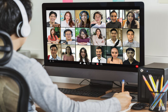 Rear View Of Asian Businessman Working And Online Meeting Via Video Conference With Colleague And Team Building When Covid-19 Pandemic,Coronavirus Outbreak,Social Distancing And New Normal Concept