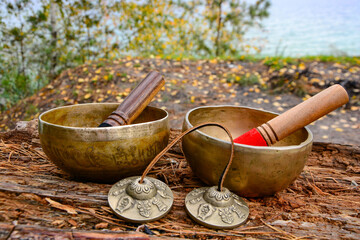 Singing bowls with Tibetan tingsha  with sticks, bell on wood in autumn background. Meditation with...