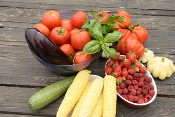 harvested vegetables. Tomatoes, corn, berries, eggplant on a wooden dark background