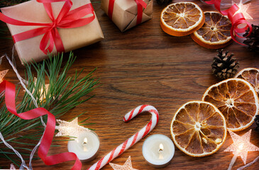 Christmas composition on a dark wooden background with gifts, toys, sweets, oranges, garlands and candles. The view from the top. Christmas. There is space for text.