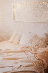 Light panel made of garlands in a white frame above the bed. Cozy modern bright bedroom. Winter Christmas interior.