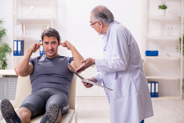 Obraz premium Young male athlete visiting old doctor radiologist