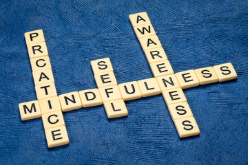 Practice mindfulness and self awareness - inspirational crossword in ivory letters against blue textured paper, personal development concept