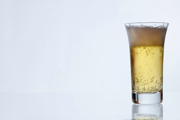 白い壁を背景に透明なグラスに入った冷えたビール