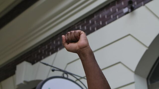 Raised African American male hand with clenched fist for protest against the background of the city street