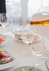 the waiter pours wine into a glass in a restaurant