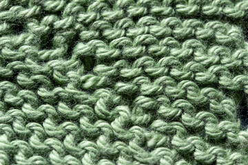 Full frame macro art abstract view of a green crocheted yarn doily texture on a dark blue background, with copy space.