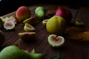 figs, pears, apples and peaches lie on a wooden table